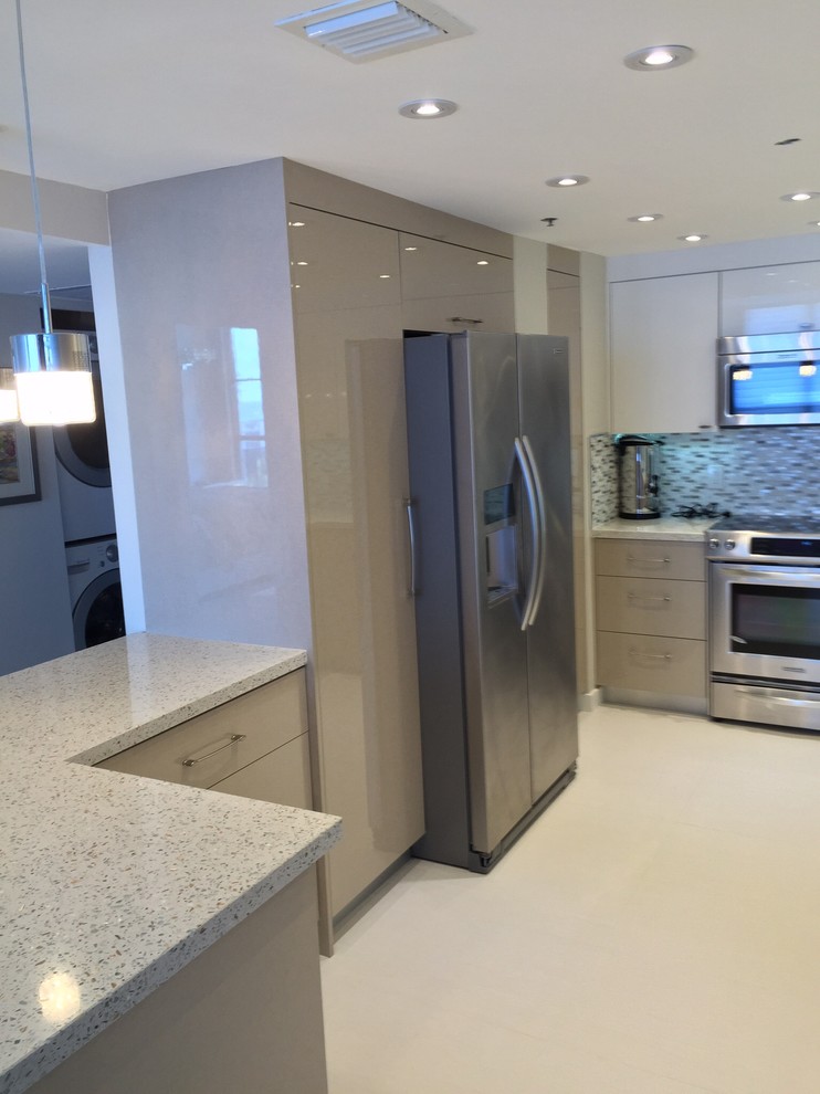 Example of a mid-sized minimalist u-shaped porcelain tile kitchen pantry design in Miami with an undermount sink, flat-panel cabinets, white cabinets, recycled glass countertops, gray backsplash, glass tile backsplash, stainless steel appliances and a peninsula