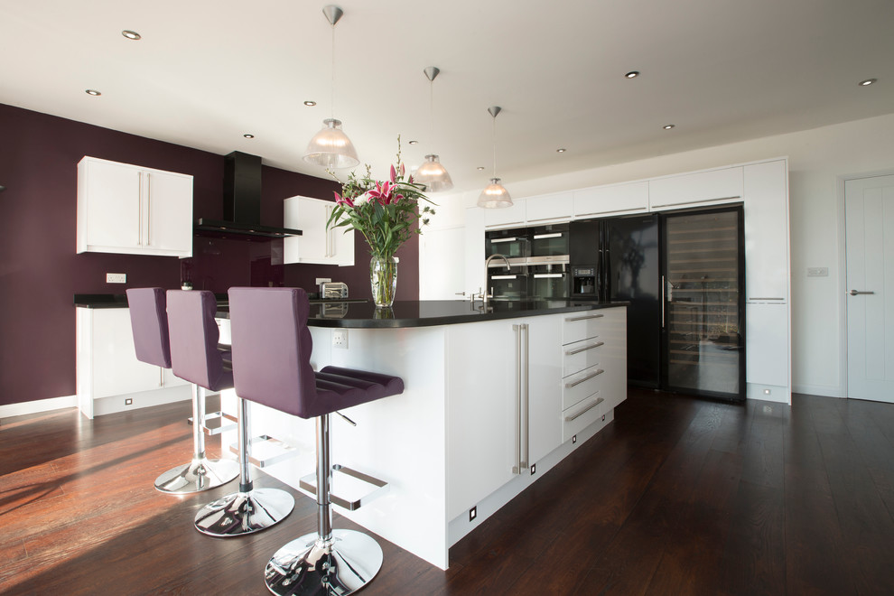 Photo of a large contemporary kitchen/diner in Other with a built-in sink, flat-panel cabinets, granite worktops, black appliances, medium hardwood flooring and an island.