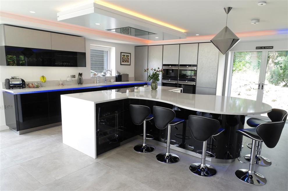 Große Moderne Wohnküche mit schwarzen Schränken, schwarzen Elektrogeräten, zwei Kücheninseln, grauem Boden und weißer Arbeitsplatte in Kent