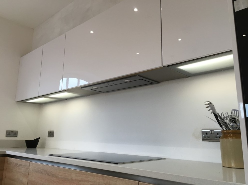 This is an example of a contemporary u-shaped kitchen/diner in Hertfordshire with quartz worktops, integrated appliances and a breakfast bar.