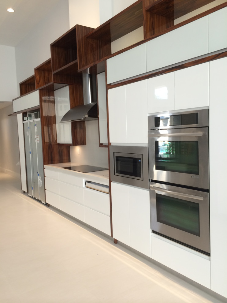 Imagen de cocina comedor lineal actual grande con armarios con paneles lisos, puertas de armario blancas, electrodomésticos de acero inoxidable y salpicadero blanco