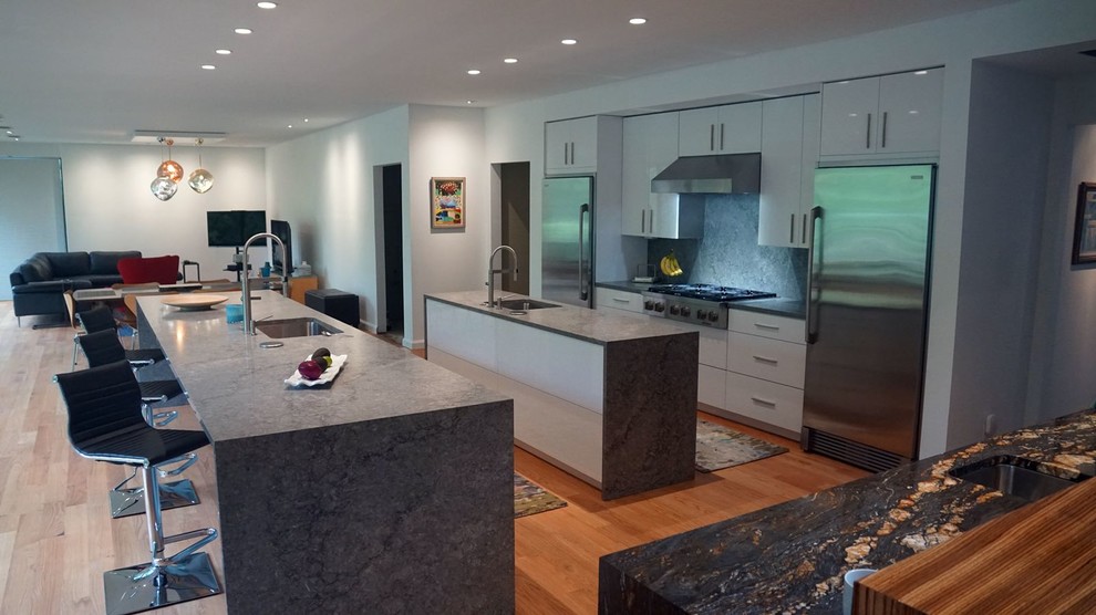 Inspiration for a huge modern galley orange floor open concept kitchen remodel in Dallas with an undermount sink, flat-panel cabinets, white cabinets, granite countertops, gray backsplash, stainless steel appliances, two islands and gray countertops