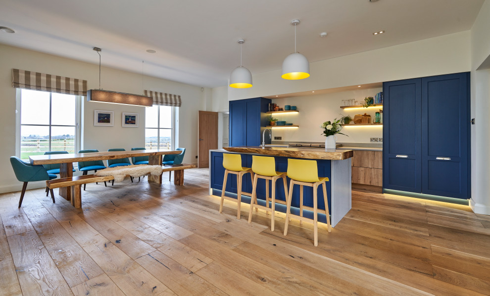 This is an example of a large contemporary single-wall open plan kitchen in Other with a built-in sink, shaker cabinets, blue cabinets, quartz worktops, grey splashback, stone tiled splashback, white appliances, medium hardwood flooring, an island, brown floors and grey worktops.