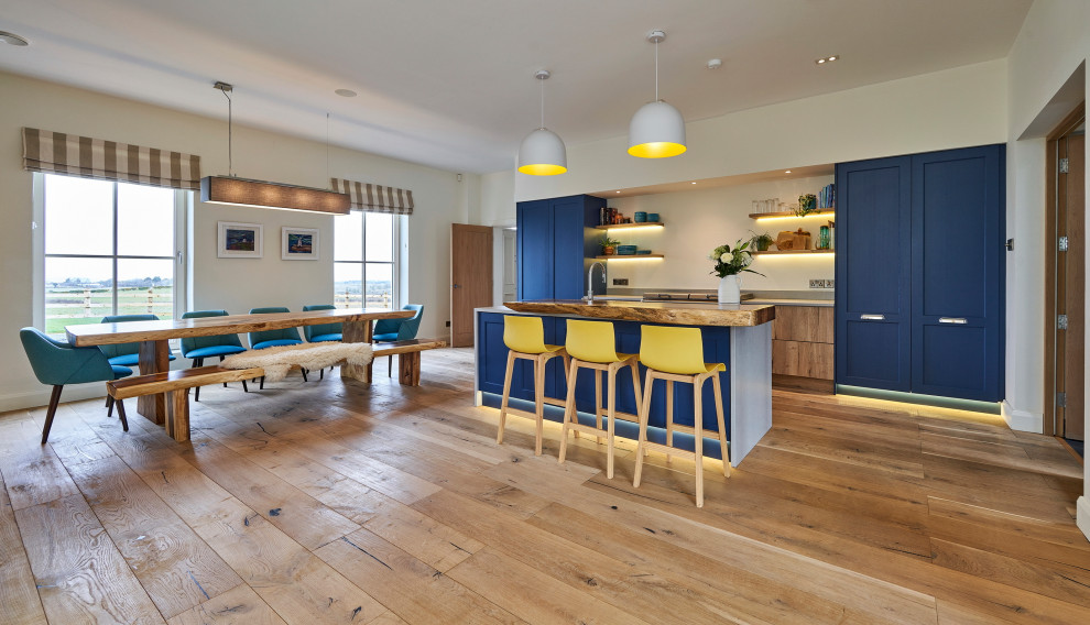 Inspiration for a large contemporary single-wall open plan kitchen in Belfast with a built-in sink, shaker cabinets, blue cabinets, quartz worktops, grey splashback, stone tiled splashback, white appliances, medium hardwood flooring, an island, brown floors and grey worktops.