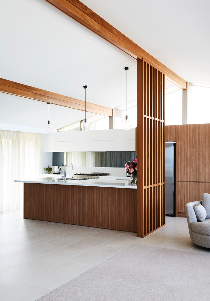 This is an example of a medium sized modern galley open plan kitchen in Sydney with a double-bowl sink, flat-panel cabinets, white cabinets, engineered stone countertops, grey splashback, mirror splashback, stainless steel appliances, ceramic flooring, an island, grey floors and white worktops.