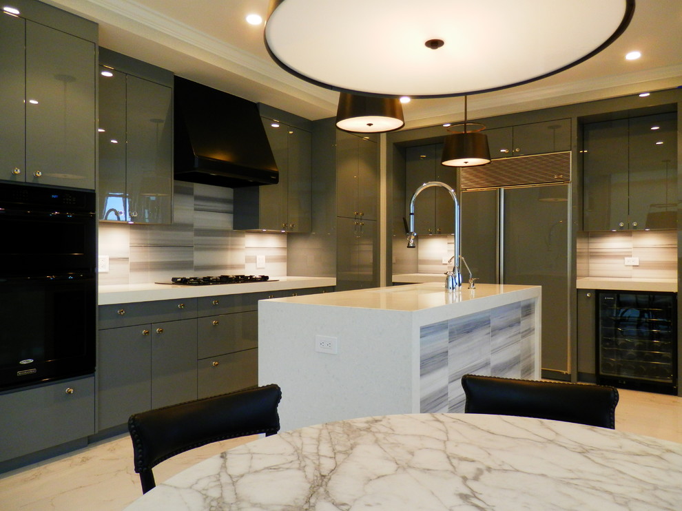 Cette image montre une cuisine américaine design en L avec un placard à porte plane, des portes de placard grises, un plan de travail en verre, un électroménager noir et îlot.