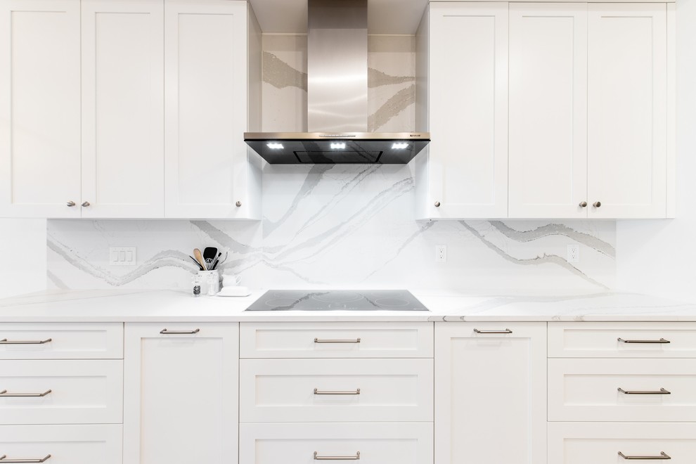 Foto på ett litet vintage vit kök, med en undermonterad diskho, skåp i shakerstil, vita skåp, bänkskiva i kvarts, vitt stänkskydd, stänkskydd i sten, svarta vitvaror, ljust trägolv och en köksö