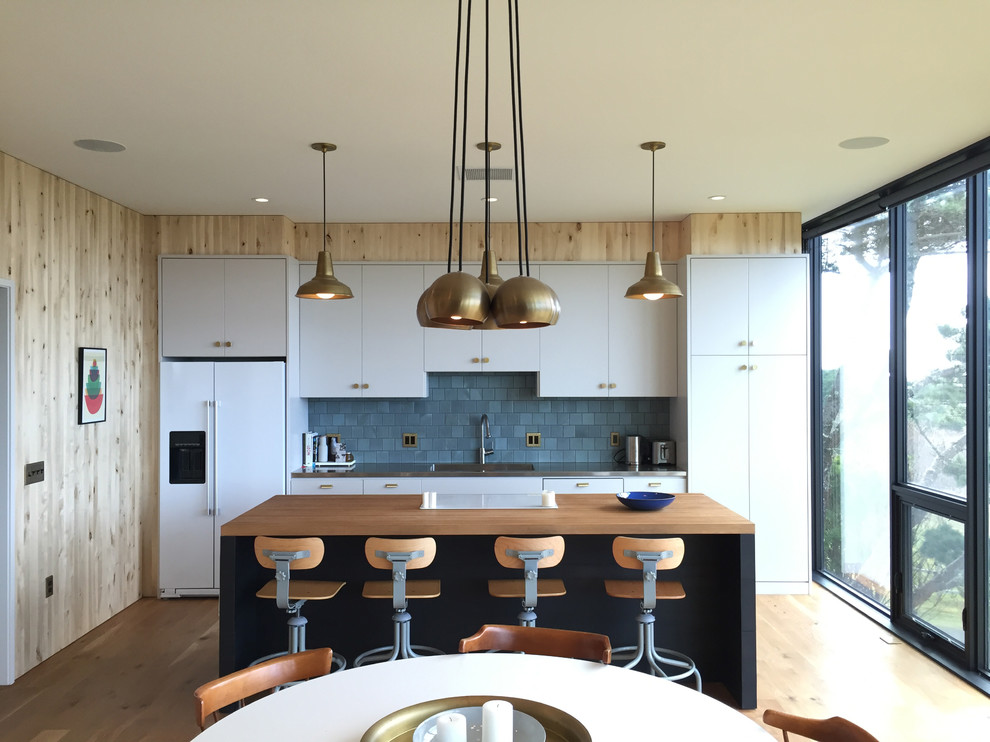 Zweizeilige Moderne Küche mit flächenbündigen Schrankfronten, Küchenrückwand in Grau, weißen Elektrogeräten, braunem Holzboden, Kücheninsel und grauen Schränken in Portland
