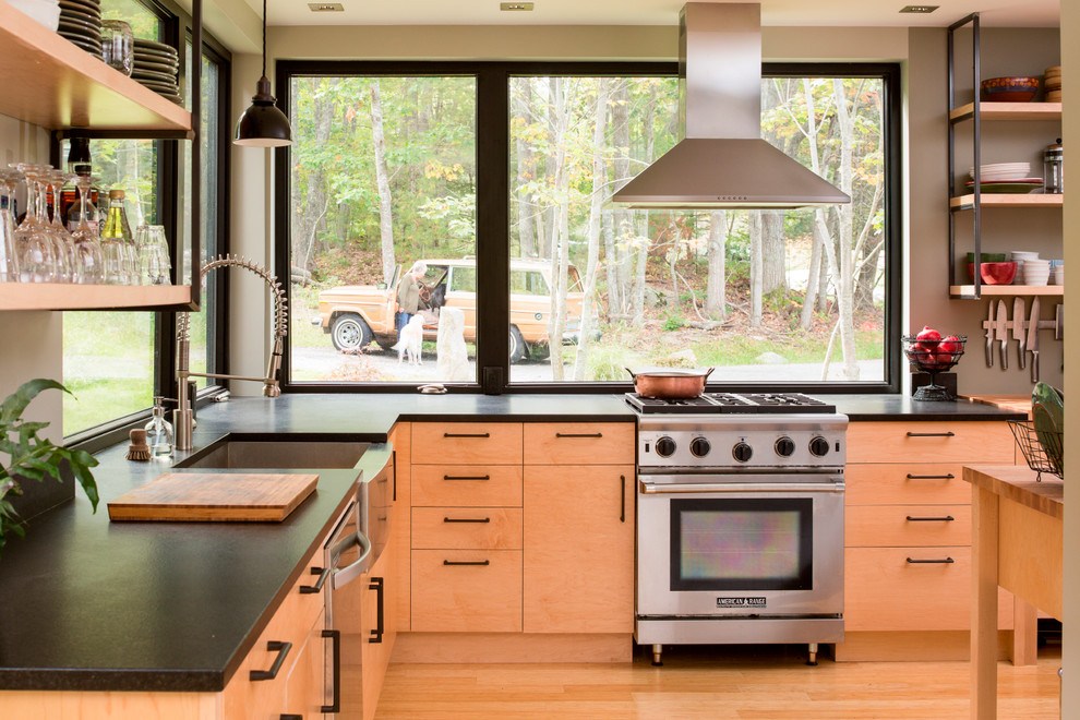 Rustikale Küche in L-Form mit Landhausspüle, flächenbündigen Schrankfronten, hellen Holzschränken, Speckstein-Arbeitsplatte, Küchengeräten aus Edelstahl, hellem Holzboden, Kücheninsel und Rückwand-Fenster in Portland Maine