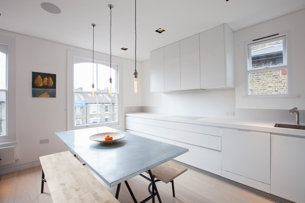 Einzeilige Moderne Wohnküche ohne Insel mit Unterbauwaschbecken, flächenbündigen Schrankfronten, weißen Schränken und hellem Holzboden in London