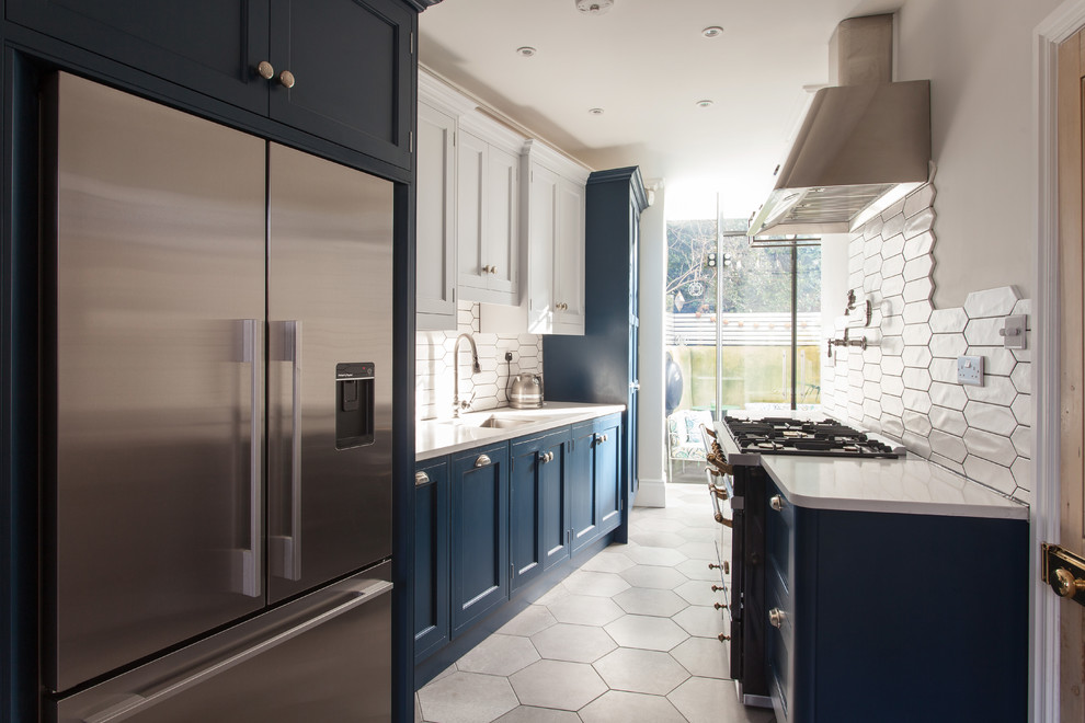 Inspiration for a small classic galley kitchen/diner in London with a submerged sink, recessed-panel cabinets, blue cabinets, white splashback, coloured appliances and grey floors.