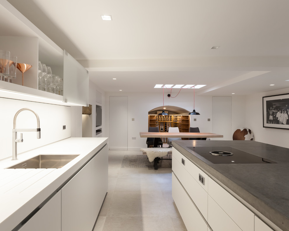 ロンドンにある高級な中くらいなコンテンポラリースタイルのおしゃれなキッチン (アンダーカウンターシンク、フラットパネル扉のキャビネット、白いキャビネット、コンクリートカウンター、白いキッチンパネル、ガラス板のキッチンパネル、シルバーの調理設備、セメントタイルの床、グレーの床、グレーのキッチンカウンター) の写真