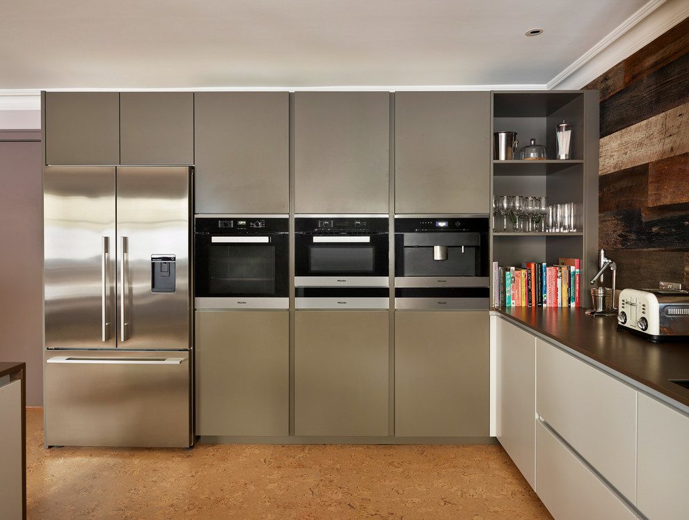 Moderne Wohnküche mit flächenbündigen Schrankfronten, grauen Schränken, Quarzit-Arbeitsplatte, Küchengeräten aus Edelstahl, Korkboden und Kücheninsel in London