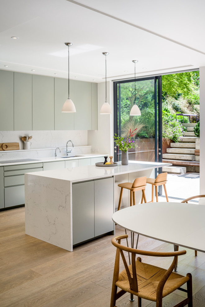 Scandi kitchen in London with flat-panel cabinets, composite countertops, white splashback, an island and white worktops.
