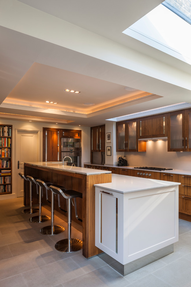 Inspiration for a mid-sized contemporary kitchen remodel in London with an island, glass-front cabinets, quartz countertops, stainless steel appliances and medium tone wood cabinets