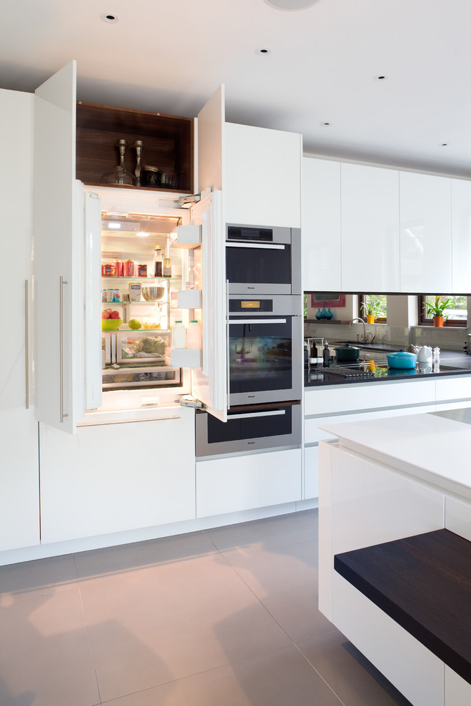 Inspiration for a contemporary kitchen remodel in London with flat-panel cabinets, white cabinets, mirror backsplash, paneled appliances and an island