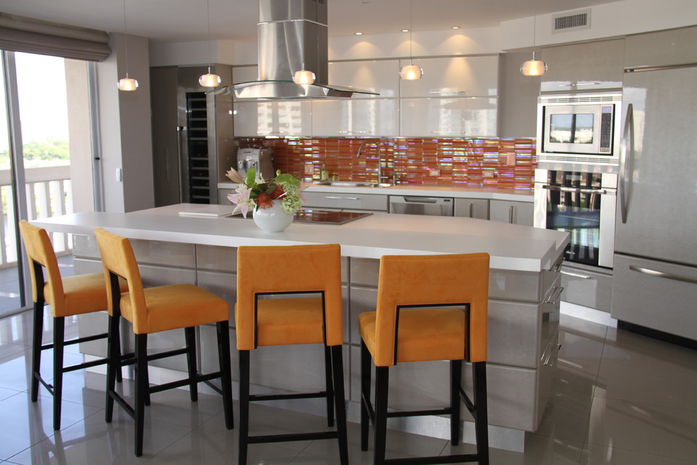 Large trendy single-wall kitchen photo in Miami with an island, flat-panel cabinets, gray cabinets, solid surface countertops, orange backsplash, glass tile backsplash, stainless steel appliances and an undermount sink