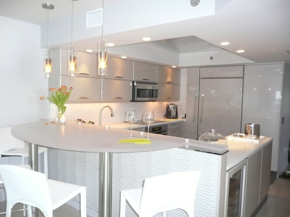 Mid-sized trendy u-shaped kitchen photo in Miami with a peninsula, flat-panel cabinets, gray cabinets, quartz countertops, white backsplash, ceramic backsplash, paneled appliances and an undermount sink