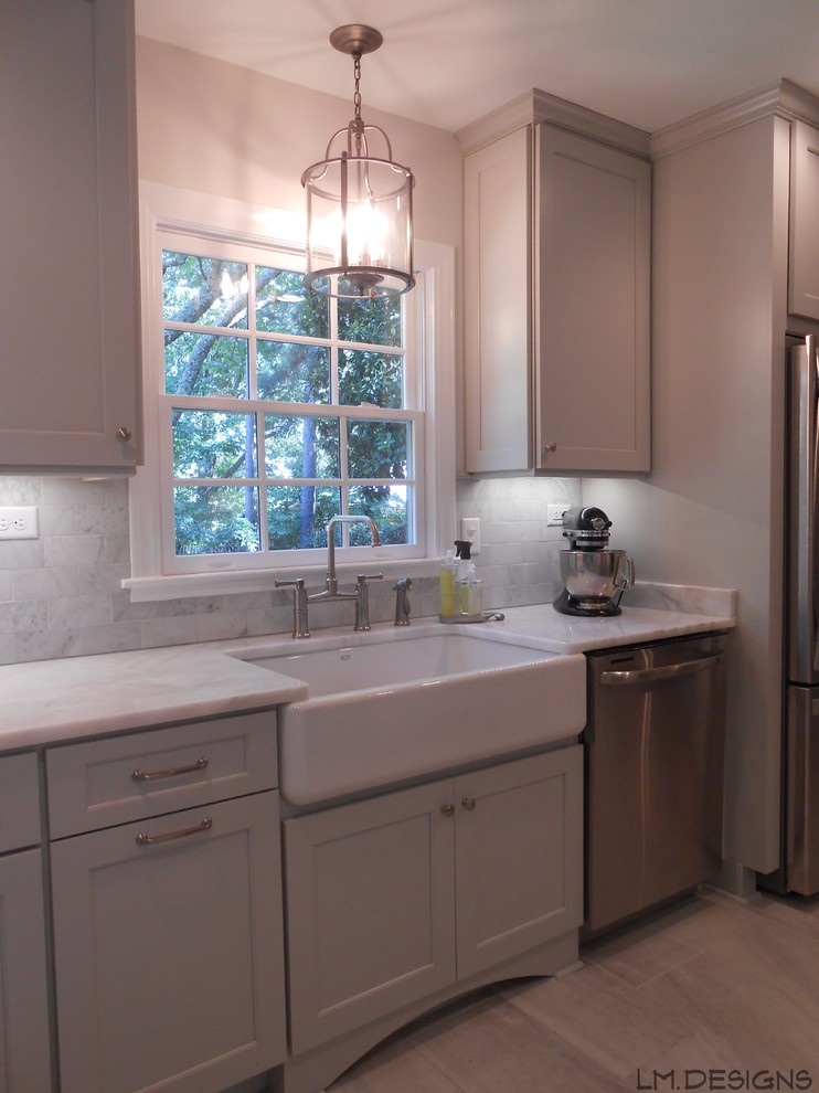 Klassisk inredning av ett kök, med en rustik diskho, luckor med infälld panel, grå skåp, marmorbänkskiva, stänkskydd i stenkakel, rostfria vitvaror, klinkergolv i porslin och en halv köksö