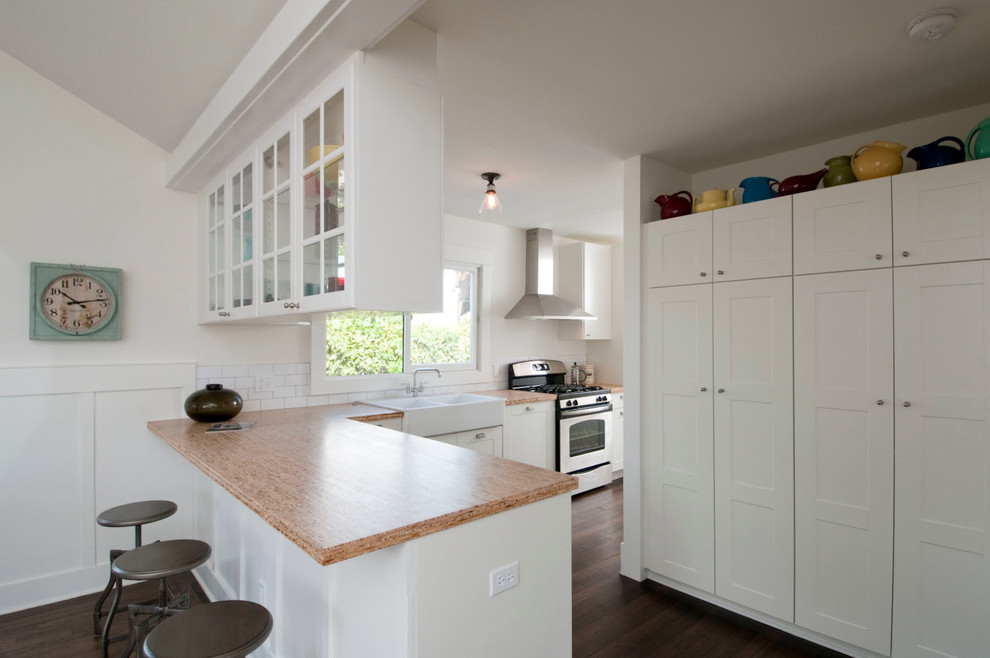 Inspiration for a mid-sized farmhouse l-shaped dark wood floor eat-in kitchen remodel in Los Angeles with a peninsula, shaker cabinets, white cabinets, white backsplash, subway tile backsplash, stainless steel appliances and a farmhouse sink