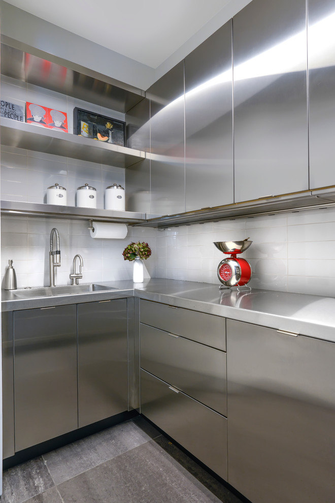 Foto på ett funkis kök, med skåp i rostfritt stål, bänkskiva i rostfritt stål, vitt stänkskydd och rostfria vitvaror