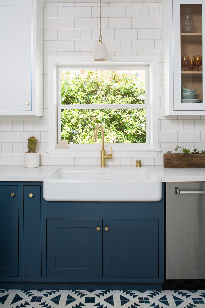Medium sized classic u-shaped enclosed kitchen in San Francisco with a belfast sink, shaker cabinets, blue cabinets, engineered stone countertops, white splashback, ceramic splashback, stainless steel appliances, cement flooring, no island and blue floors.