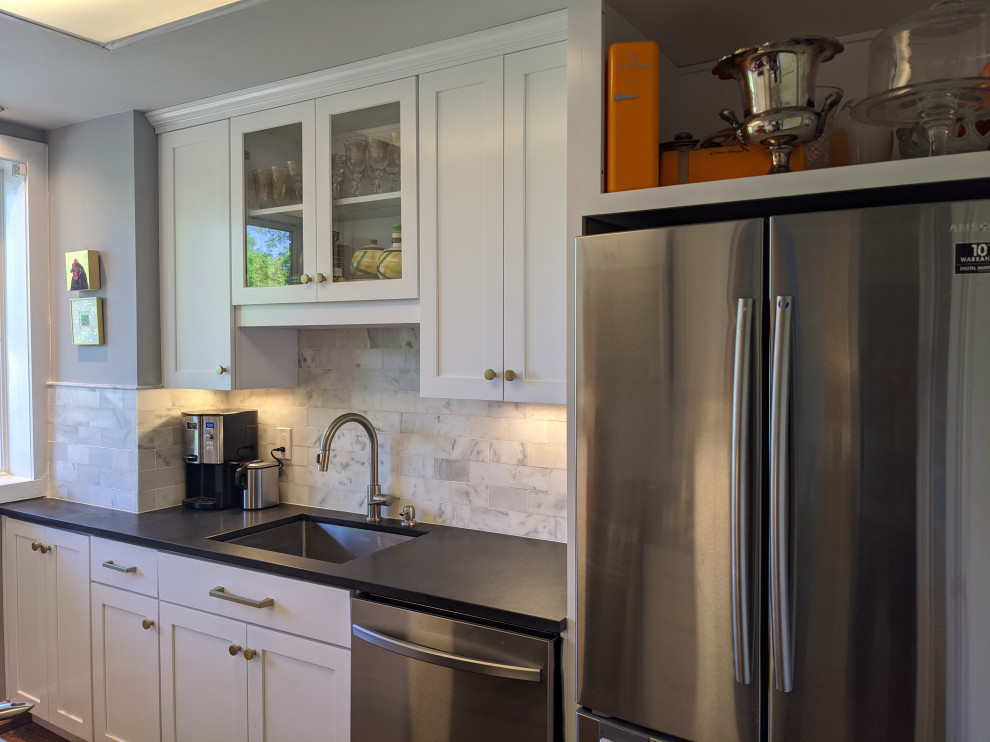 Example of a small classic galley medium tone wood floor and brown floor eat-in kitchen design in Birmingham with an undermount sink, shaker cabinets, white cabinets, soapstone countertops, gray backsplash, marble backsplash, stainless steel appliances, no island and black countertops
