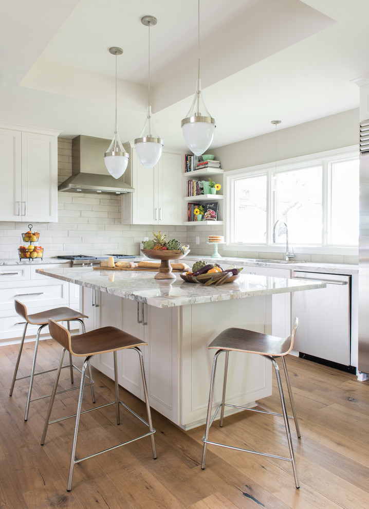 Inspiration for a large mid-century modern l-shaped medium tone wood floor eat-in kitchen remodel in Austin with an undermount sink, shaker cabinets, white cabinets, marble countertops, white backsplash, subway tile backsplash, stainless steel appliances and an island