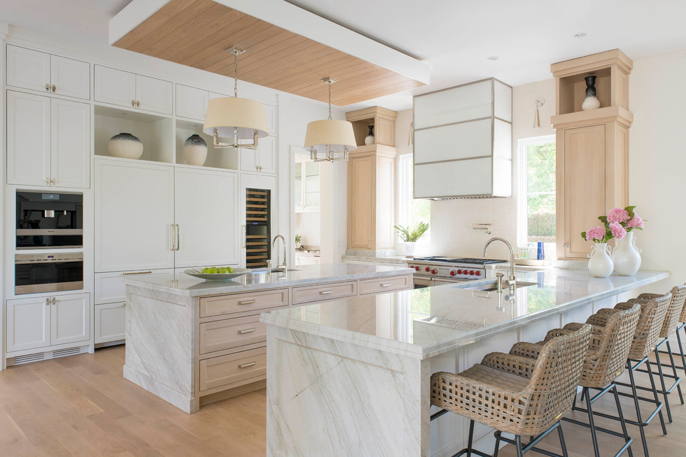 Bild på ett medelhavsstil u-kök, med en undermonterad diskho, skåp i shakerstil, bänkskiva i kvartsit, vitt stänkskydd, stänkskydd i keramik, ljust trägolv, en köksö, vita skåp, integrerade vitvaror och beiget golv