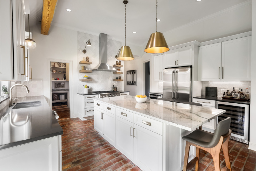 Large u-shaped brick floor and brown floor eat-in kitchen photo in New Orleans with an undermount sink, recessed-panel cabinets, white cabinets, quartzite countertops, white backsplash, subway tile backsplash, stainless steel appliances, an island and gray countertops