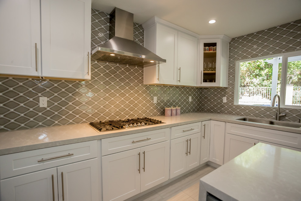 Large transitional u-shaped porcelain tile open concept kitchen photo in Los Angeles with a single-bowl sink, shaker cabinets, white cabinets, quartzite countertops, gray backsplash, porcelain backsplash, stainless steel appliances and an island
