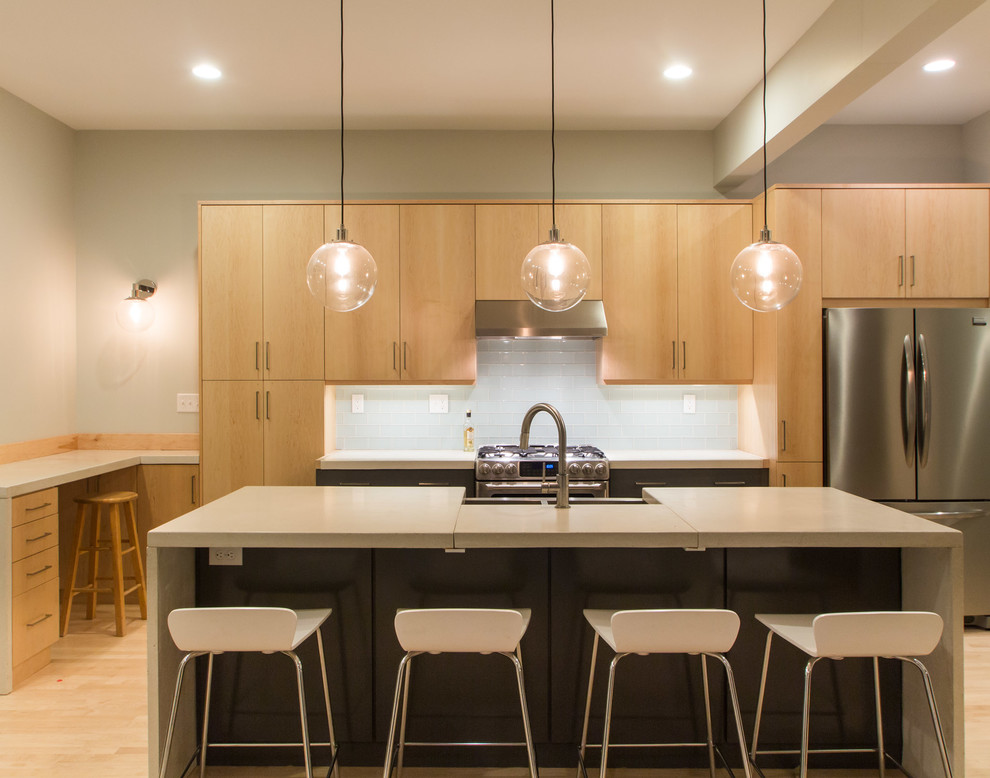 Example of a large trendy galley light wood floor eat-in kitchen design in Louisville with a double-bowl sink, flat-panel cabinets, light wood cabinets, concrete countertops, white backsplash, glass tile backsplash, stainless steel appliances and an island