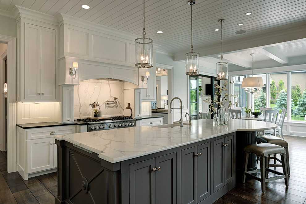 Example of a large classic l-shaped medium tone wood floor eat-in kitchen design in Kansas City with a farmhouse sink, flat-panel cabinets, white cabinets, quartzite countertops, white backsplash, stone slab backsplash, paneled appliances, an island and multicolored countertops