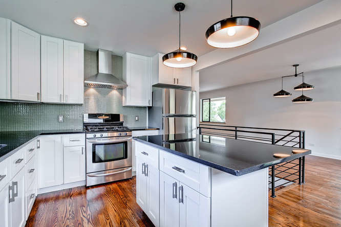 Example of a mid-sized transitional galley medium tone wood floor open concept kitchen design in Denver with an undermount sink, shaker cabinets, white cabinets, quartzite countertops, green backsplash, glass tile backsplash, stainless steel appliances and an island