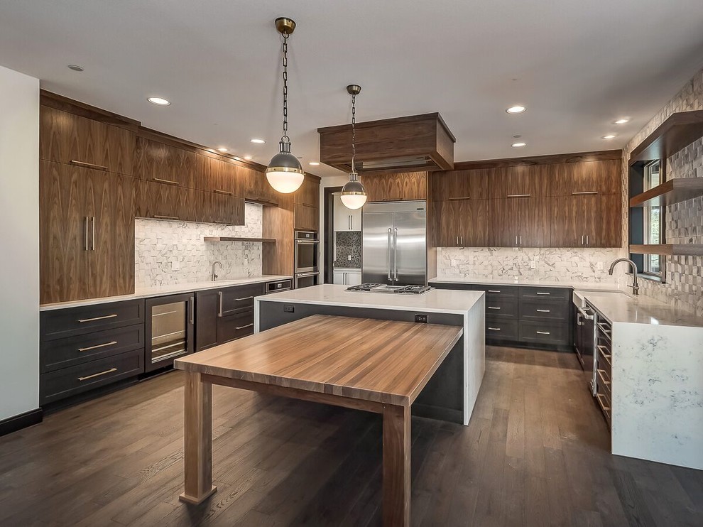 Large minimalist u-shaped dark wood floor and brown floor open concept kitchen photo in Portland with a farmhouse sink, flat-panel cabinets, medium tone wood cabinets, quartzite countertops, white backsplash, marble backsplash, stainless steel appliances and an island