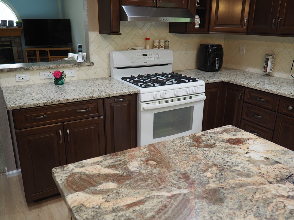 Foto på ett litet vintage flerfärgad kök, med en undermonterad diskho, luckor med upphöjd panel, granitbänkskiva, vitt stänkskydd, stänkskydd i keramik, vita vitvaror, laminatgolv, en köksö och flerfärgat golv