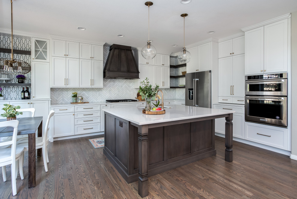 Large transitional galley medium tone wood floor and brown floor open concept kitchen photo in Denver with an undermount sink, shaker cabinets, white cabinets, quartz countertops, beige backsplash, marble backsplash, stainless steel appliances, an island and white countertops