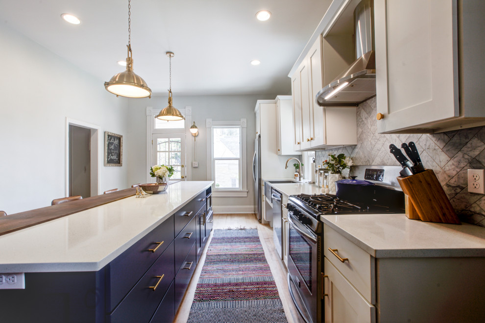 Bild på ett mellanstort vintage vit vitt kök, med en rustik diskho, skåp i shakerstil, blå skåp, bänkskiva i kvartsit, grått stänkskydd, stänkskydd i stenkakel, rostfria vitvaror, mellanmörkt trägolv och en köksö