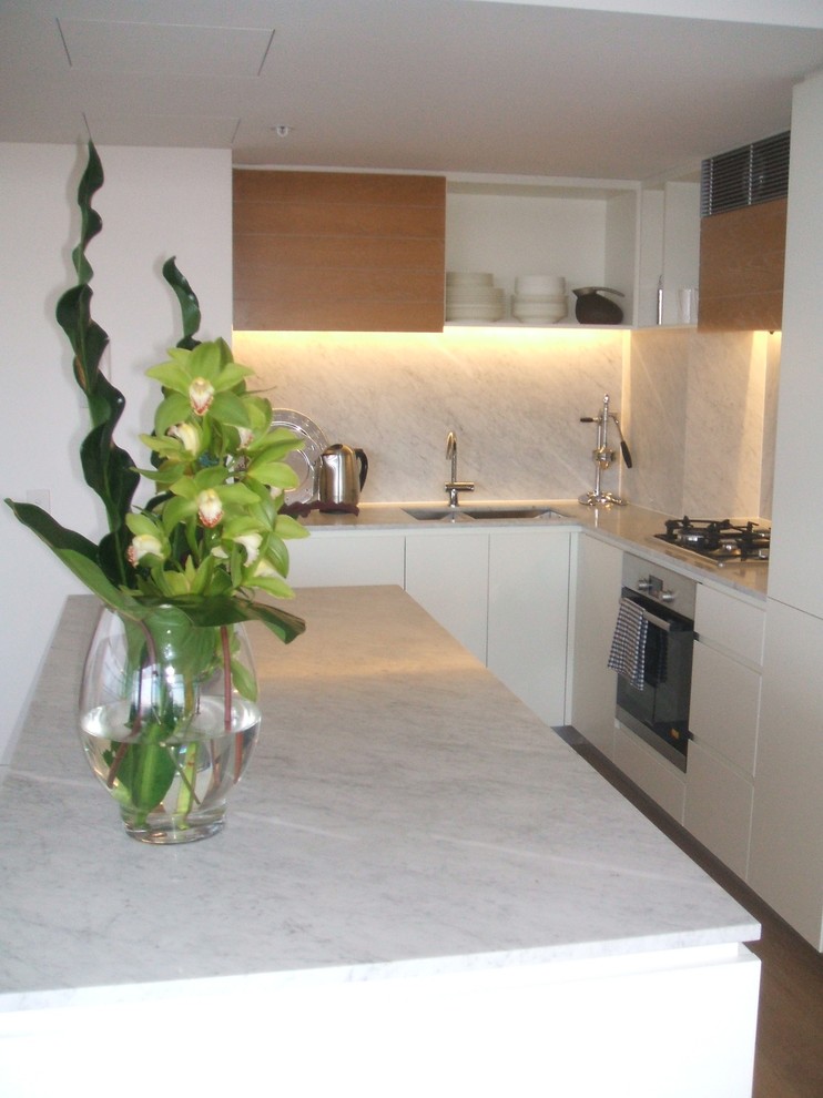 Ispirazione per un piccolo cucina con isola centrale minimal con ante in legno chiaro, top in marmo e paraspruzzi bianco