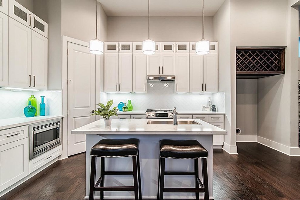 Inspiration for a mid-sized transitional u-shaped dark wood floor eat-in kitchen remodel in Houston with an undermount sink, shaker cabinets, white cabinets, quartz countertops, white backsplash, subway tile backsplash, stainless steel appliances and an island