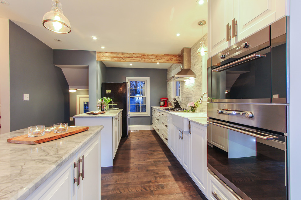 Eat-in kitchen - mid-sized transitional u-shaped dark wood floor eat-in kitchen idea in Calgary with a farmhouse sink, white cabinets, marble countertops, gray backsplash, stainless steel appliances, two islands, raised-panel cabinets and marble backsplash