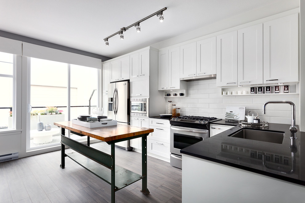Eat-in kitchen - contemporary single-wall medium tone wood floor eat-in kitchen idea in Vancouver with an undermount sink, shaker cabinets, white cabinets, granite countertops, white backsplash, cement tile backsplash and stainless steel appliances
