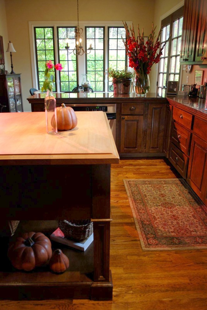 Aménagement d'une cuisine classique en bois foncé avec un placard avec porte à panneau surélevé, un plan de travail en bois et un sol marron.