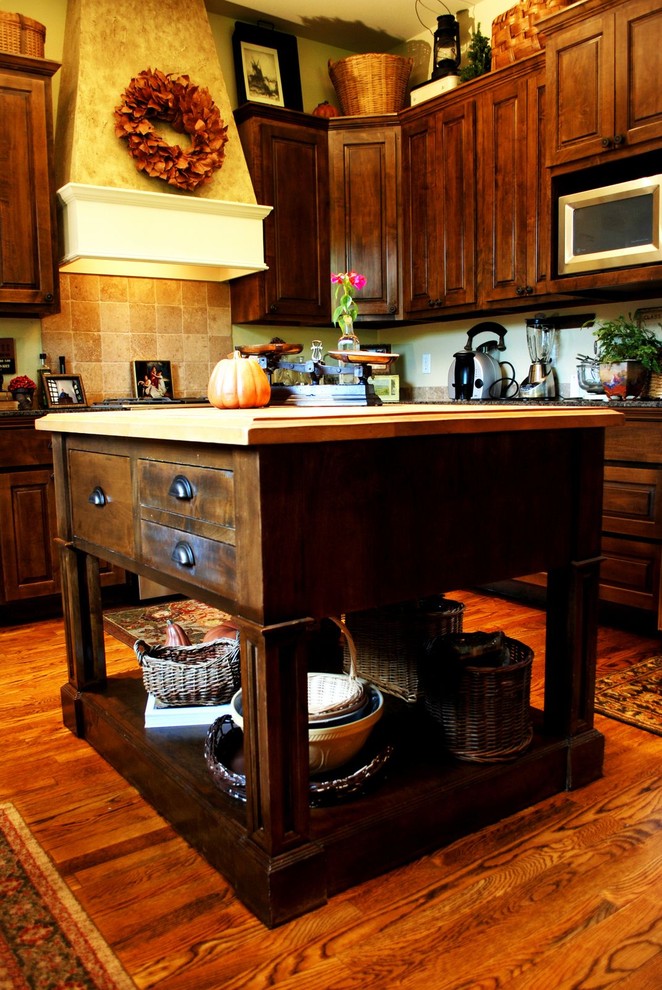 Elegant kitchen photo in Austin with wood countertops, raised-panel cabinets, dark wood cabinets and beige backsplash