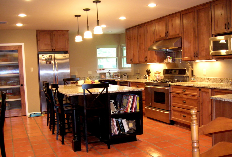 Bild på ett stort lantligt kök, med en rustik diskho, släta luckor, skåp i mellenmörkt trä, granitbänkskiva, beige stänkskydd, stänkskydd i sten, rostfria vitvaror, klinkergolv i terrakotta och en köksö