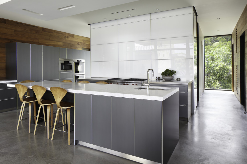 Aménagement d'une cuisine parallèle et grise et blanche contemporaine avec un placard à porte plane et des portes de placard grises.