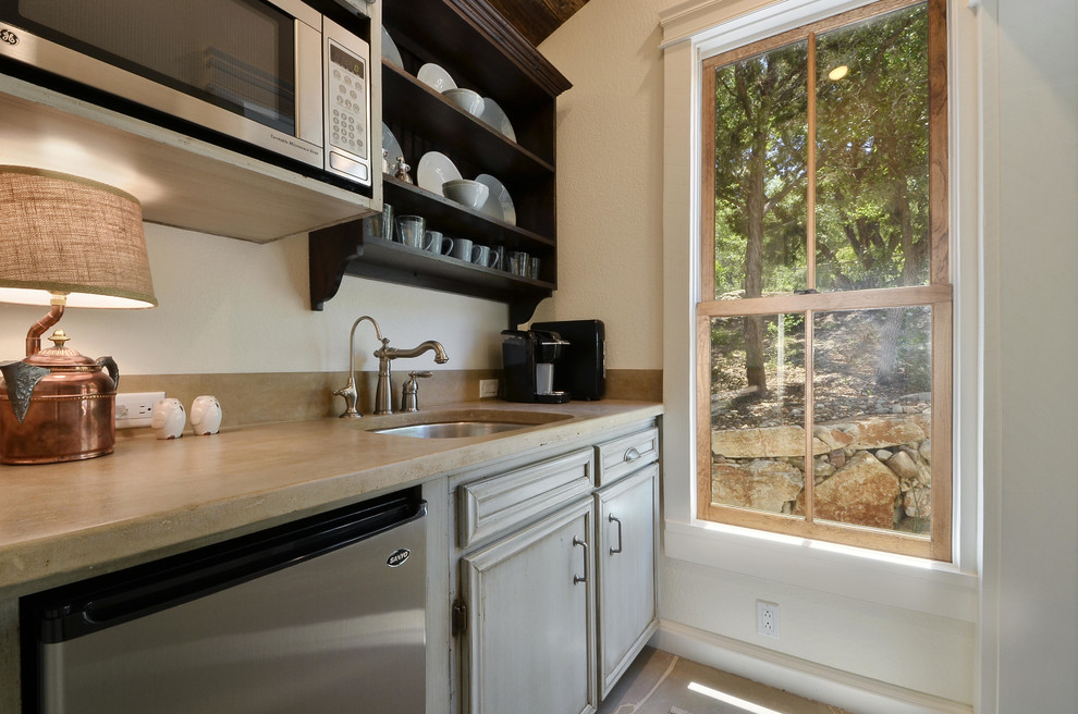 Cette image montre une petite cuisine parallèle chalet en bois vieilli fermée avec un évier encastré, un plan de travail en calcaire, une crédence en dalle de pierre, un électroménager en acier inoxydable et un sol en calcaire.