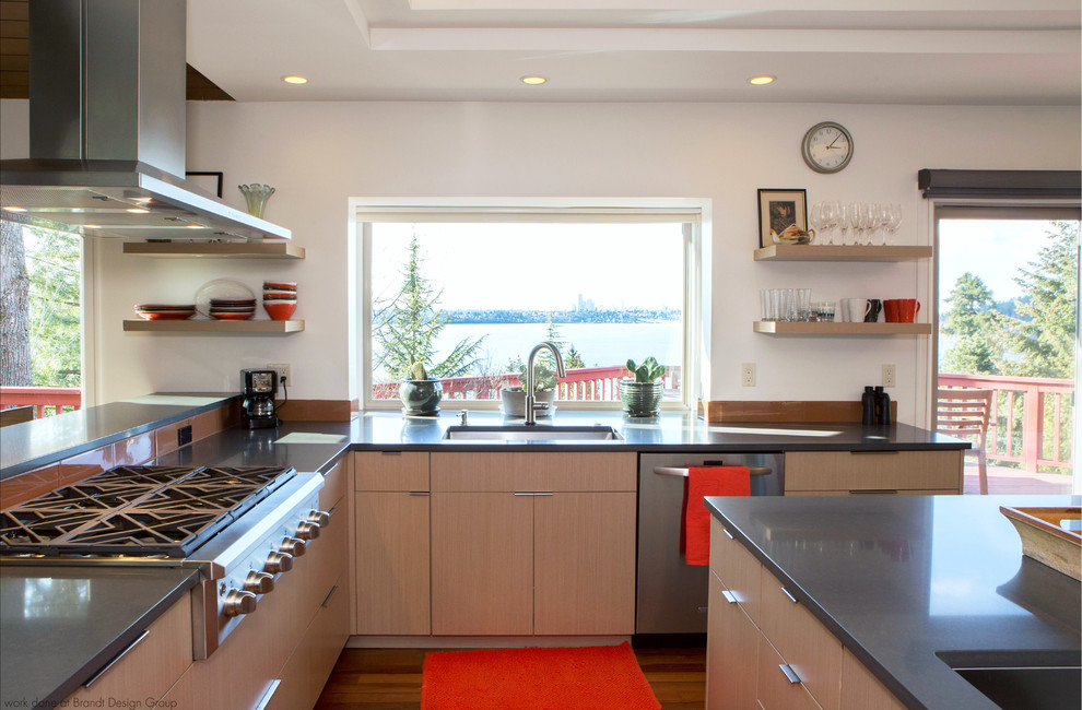 Cette image montre une cuisine design en bois clair avec un évier encastré, un placard à porte plane, un plan de travail en quartz modifié, une crédence orange, une crédence en carreau de verre, îlot et un plan de travail gris.