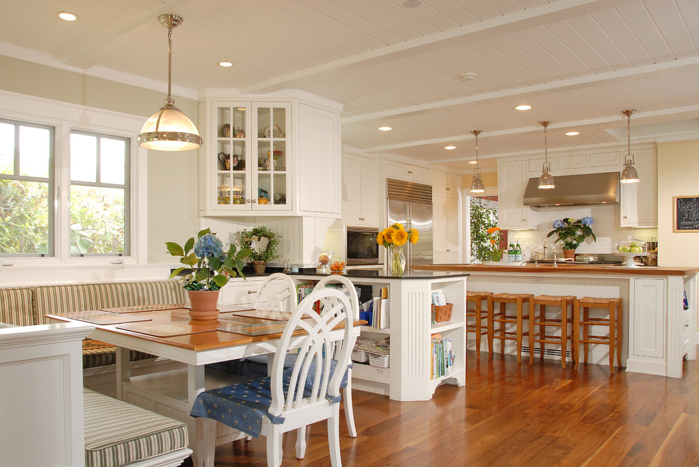 На фото: кухня в классическом стиле с обеденным столом, фасадами в стиле шейкер, белыми фасадами и техникой из нержавеющей стали