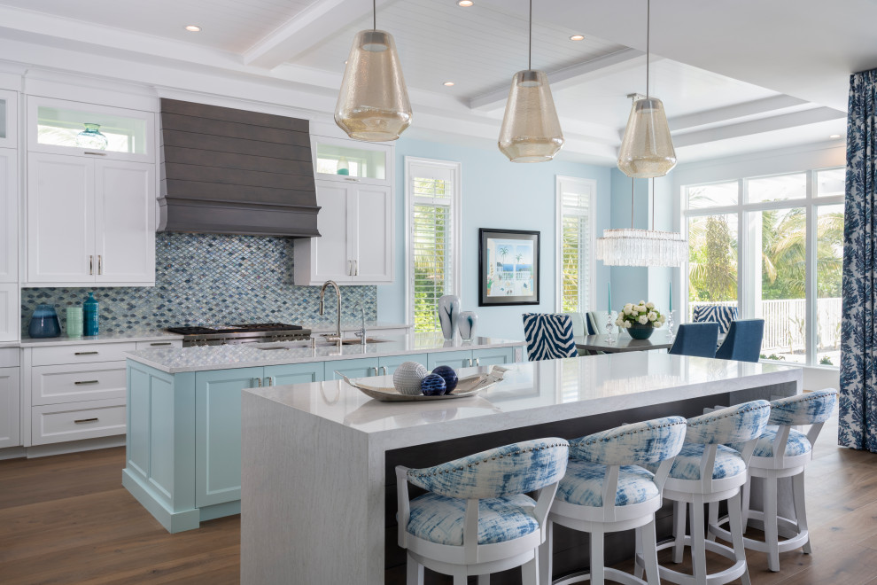 Bild på ett maritimt vit vitt kök och matrum, med en undermonterad diskho, skåp i shakerstil, vita skåp, blått stänkskydd, stänkskydd i mosaik, mellanmörkt trägolv, flera köksöar och brunt golv